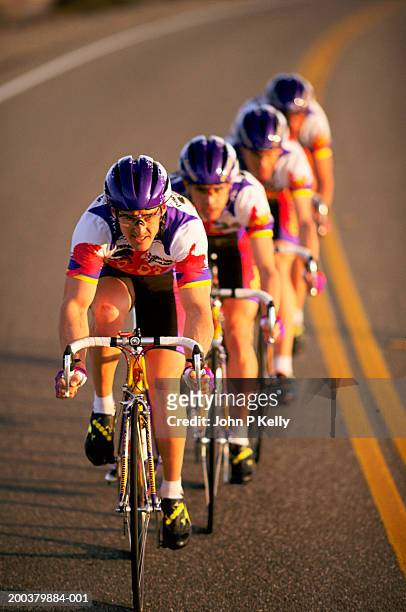 road racing cyclist team riding in formation (focus on foreground) - radsport wettbewerb stock-fotos und bilder
