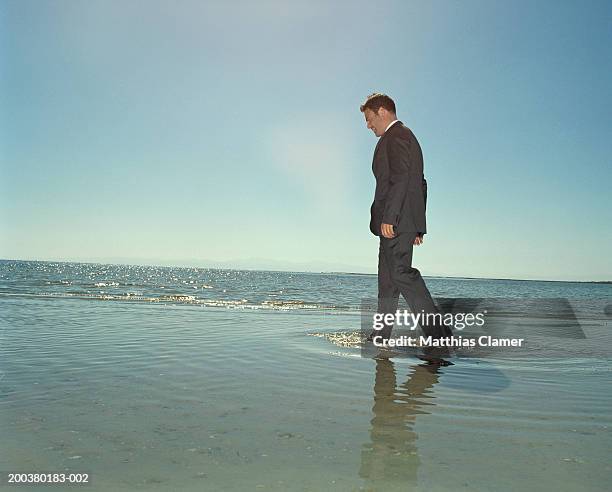 businessman walking through ocean, side view - ankle deep in water stock pictures, royalty-free photos & images