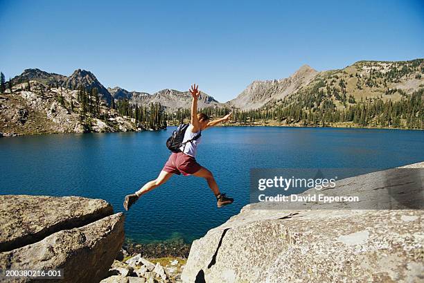 young woman jumping between rocks, side view, - crevice stock pictures, royalty-free photos & images