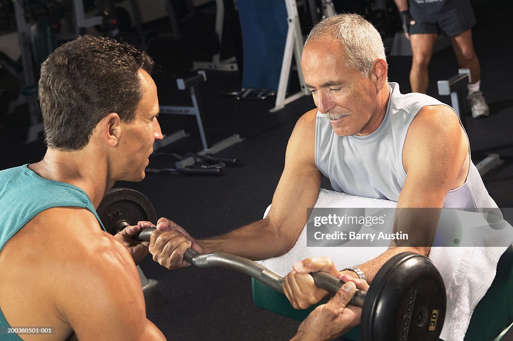 Mature man weight training with male fitness instructor