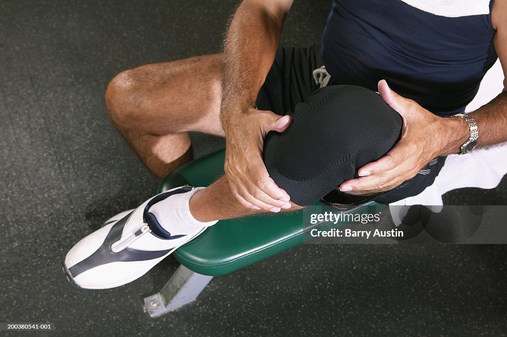 Senior man in gym wearing knee strap, lifting knee, overhead view