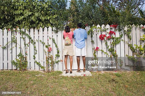 young couple looking over white picket fence, rear view - white picket gate stock pictures, royalty-free photos & images