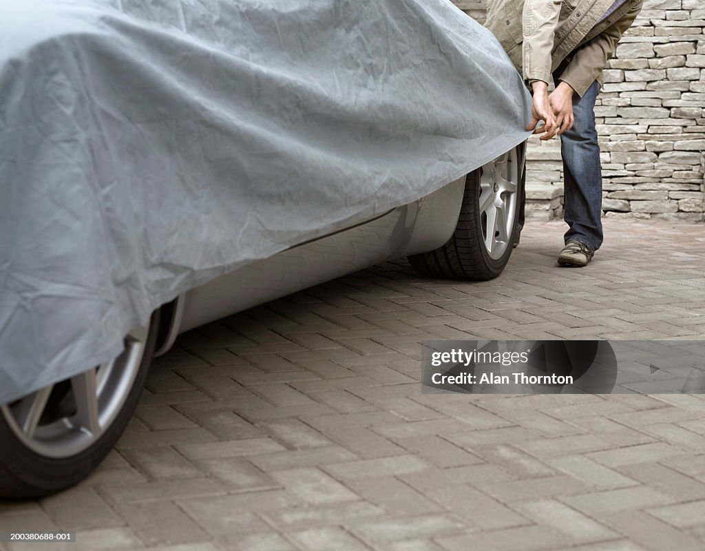 Young man putting protective sheet on car