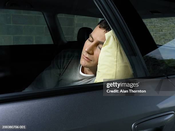 young man asleep in car, view through window - auto schlafen stock-fotos und bilder