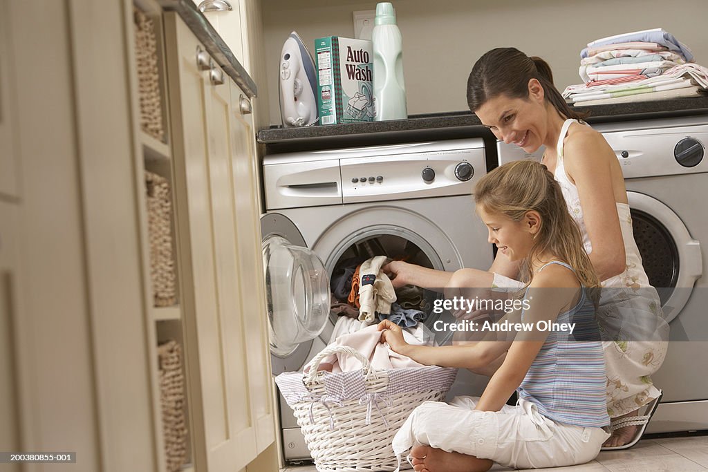 Mother and daughter (7-9) sitting on floor sorting through laundry