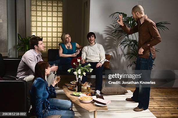 group of men and women playing charades in lounge, man miming - pantomime stock pictures, royalty-free photos & images