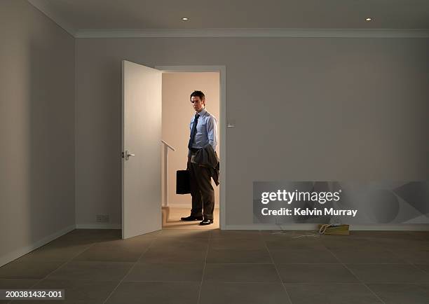 businessman standing in hall by doorway into empty room - premiere of winterstone pictures deserted arrivals stockfoto's en -beelden