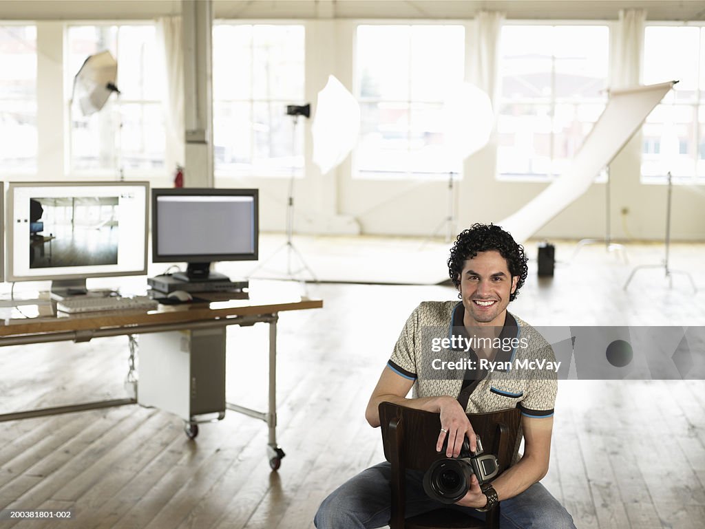 Young male photographer holding camera in photo studio, portrait