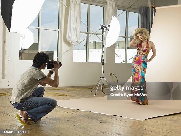 man photographing young female model on set in photo studio - atelier mode stock-fotos und bilder