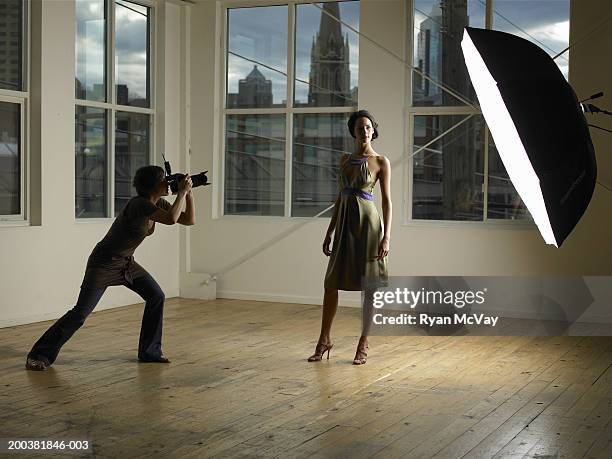 woman photographing young female model in photo studio, dusk - fashion shoot stock-fotos und bilder