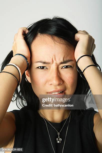 young woman frowning, biting lips, hands on head, portrait, close-up - biting lip ストックフォトと画像