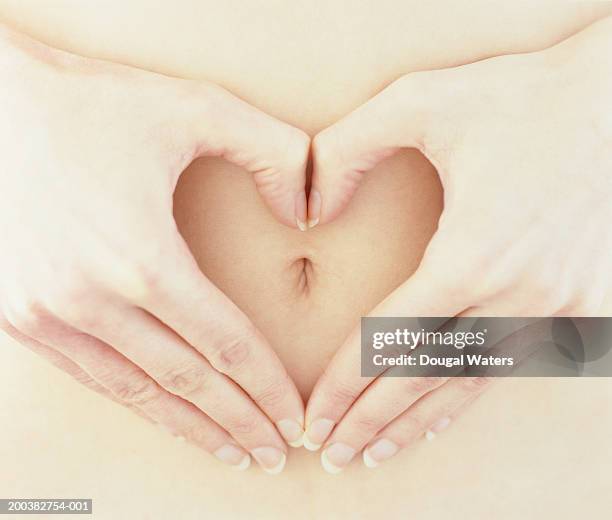 woman making heart shape with hands around belly button, close-up - belly button ストックフォトと画像