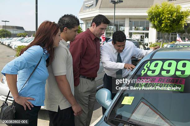 car salesman showing car to couple with adult son, outdoors - auto sticker price stock pictures, royalty-free photos & images