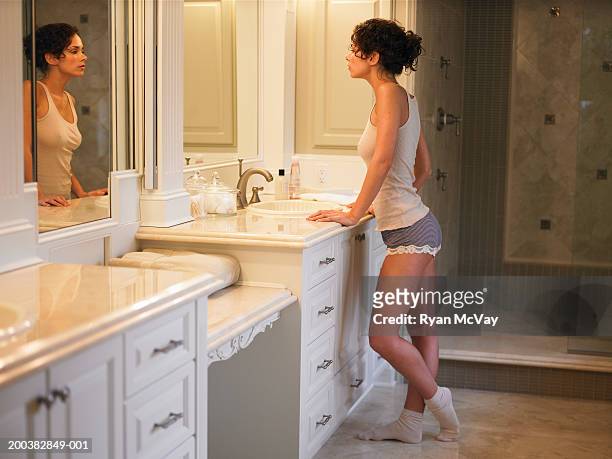 young woman looking in bathroom mirror, side view - full length mirror fotografías e imágenes de stock
