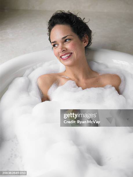 young woman soaking in bubble bath, smiling, elevated view - beautiful woman bath photos et images de collection