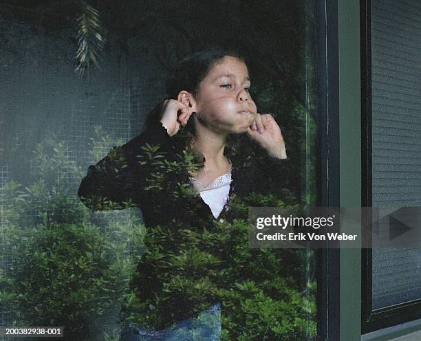 girl (8-10) making face, pulling ears behind glass - human ear stockfoto's en -beelden