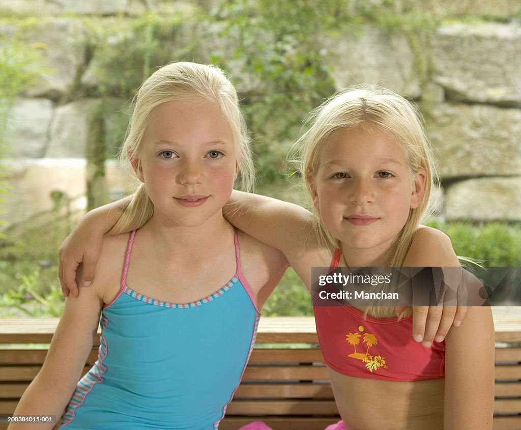 Two girls (8-10) wearing swimsuits and arms around shoulders, portrait