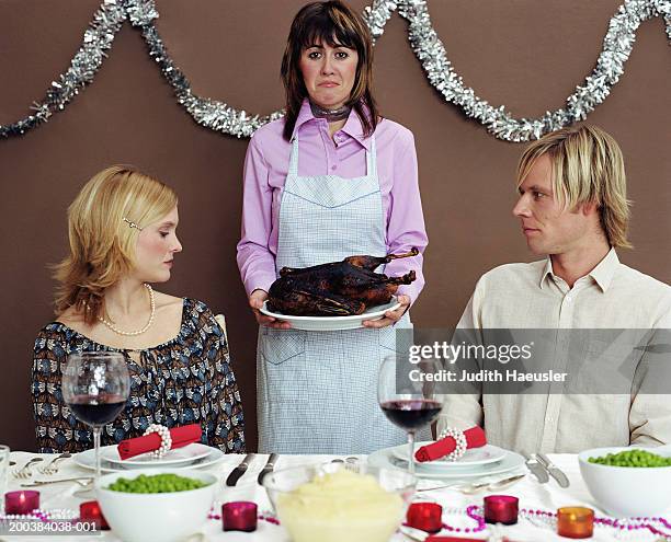 woman holding burnt duck by friends at table, pulling face, portrait - awkward dinner stock pictures, royalty-free photos & images
