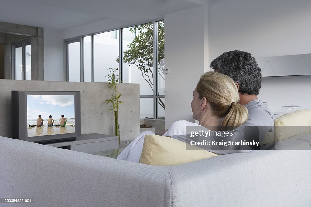 Couple relaxing on sofa watching television, rear view