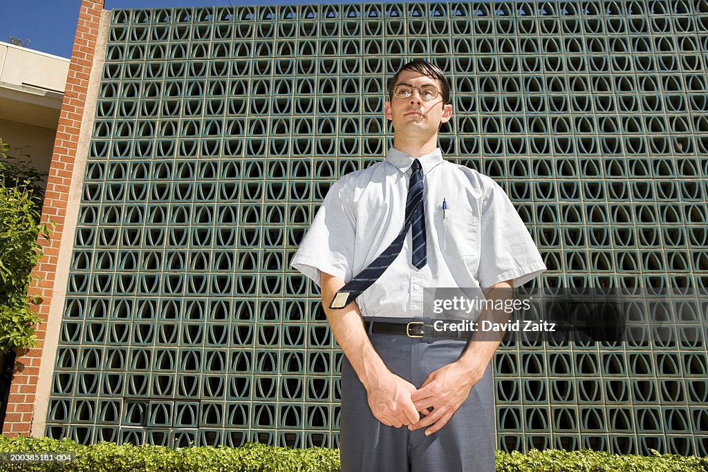 Businessman in front of wall, low angle view, close-up