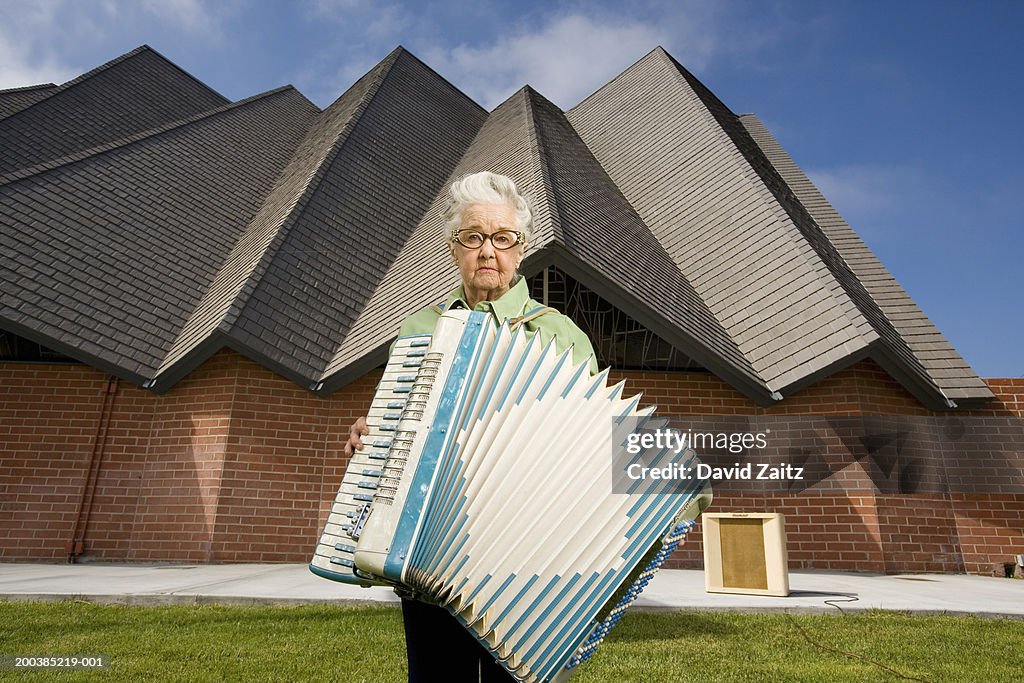 Elderly woman with accordion in front of church, portrait