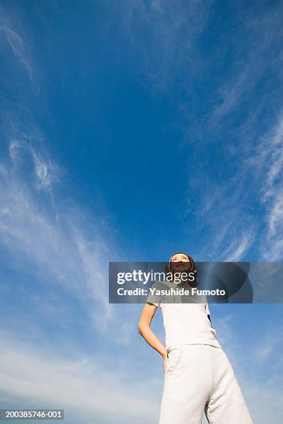 woman standing outdoors, hands on hips, smiling, low angle view - hand in die hüfte gestemmt stock-fotos und bilder