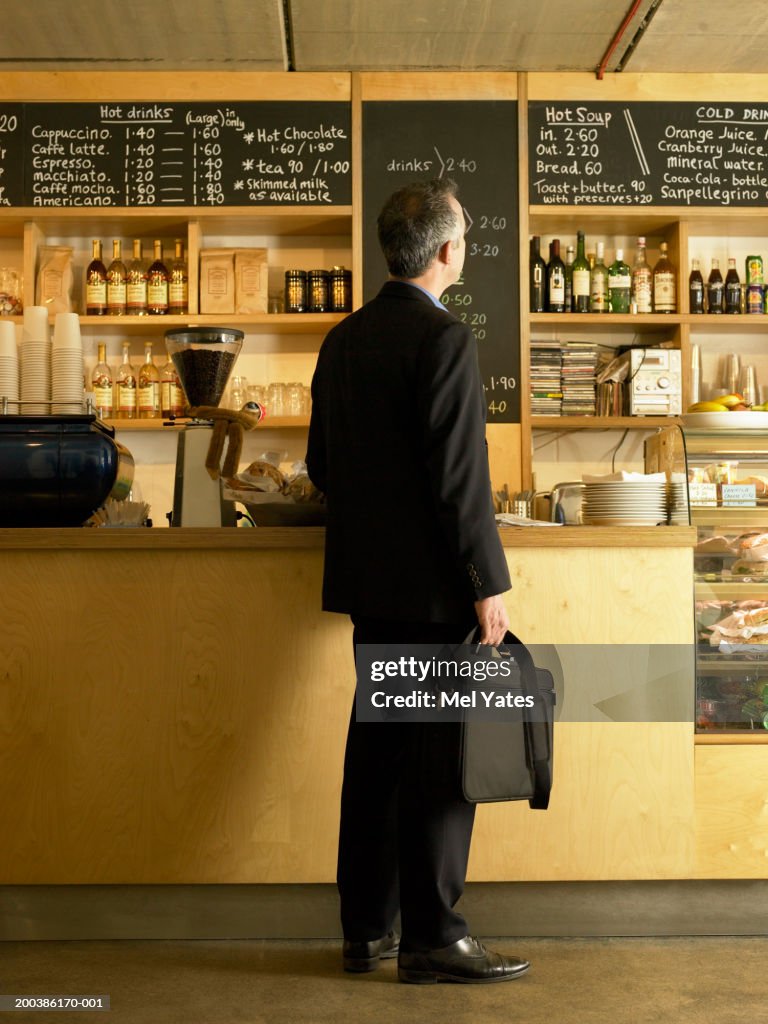 Businessman standing at counter in cafe, rear view