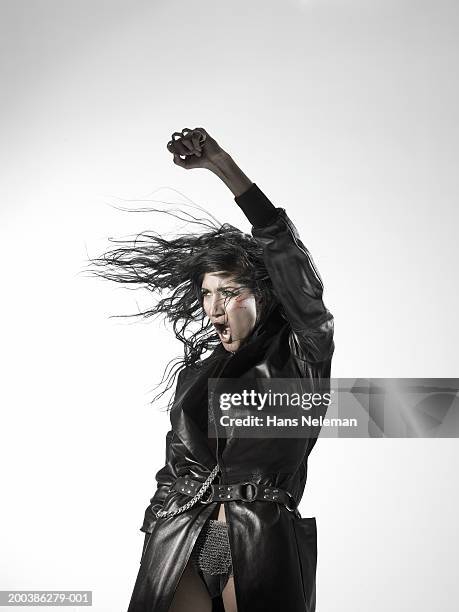 woman wearing a black leather trench coat, shouting, left arm raised - knuckle duster imagens e fotografias de stock