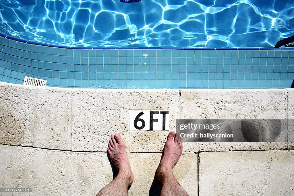 Man's bare feet beside pool, low section, overhead view