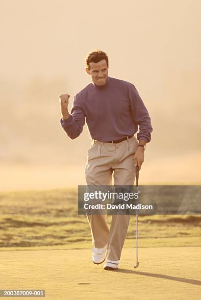 mature man pumping fist after sinking putt on golf course (soft focus) - golf excitement stock pictures, royalty-free photos & images