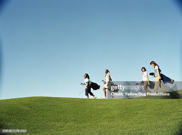 female golfers carrying golf bags, side view - women's golf stockfoto's en -beelden