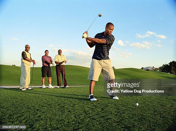 male golfer driving ball, friends watching (blurred motion) - golfer stock pictures, royalty-free photos & images