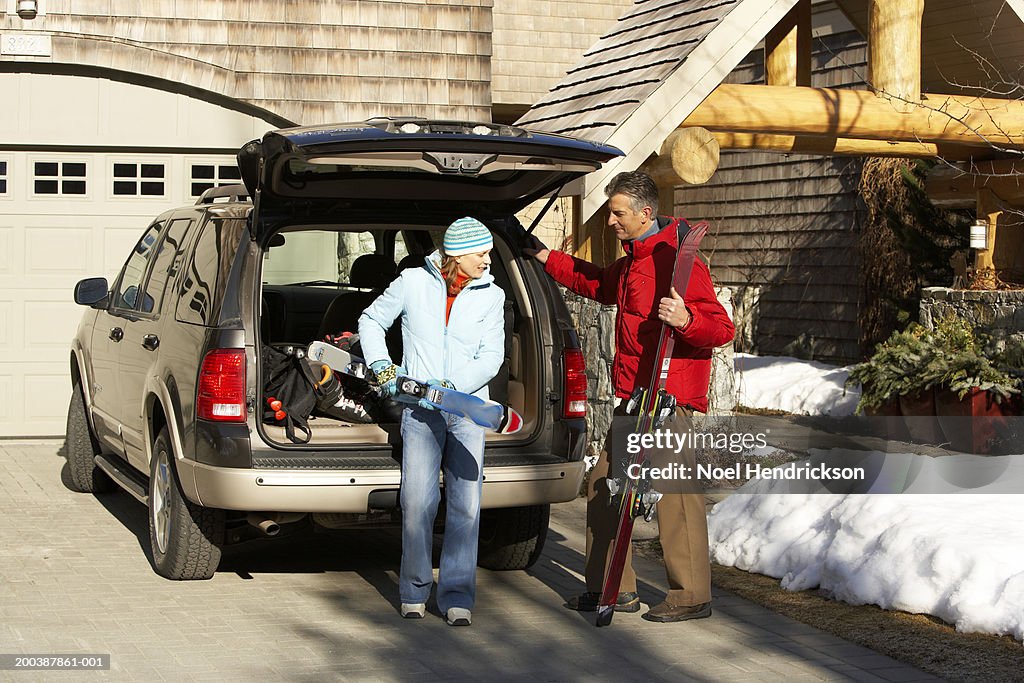 Couple removing skis from back of vehicle