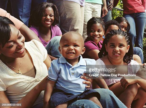 male toddler (12-15 months) sitting on woman's lap at family reunion - black family reunion stock-fotos und bilder
