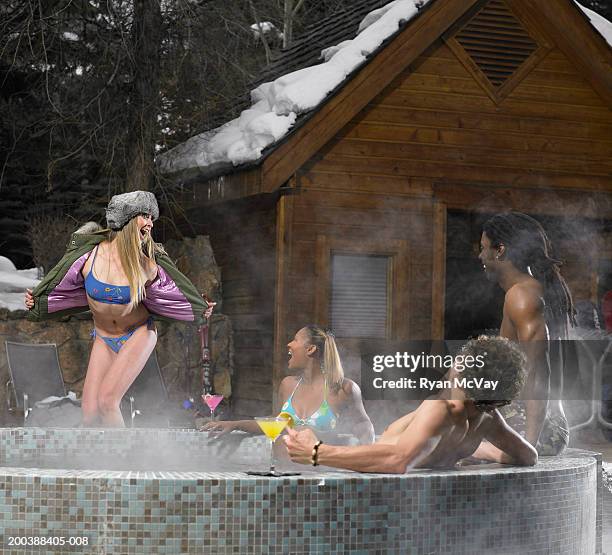 four young adults drinking alcohol and soaking in hot tub, winter - アフタースキー ストックフォトと画像