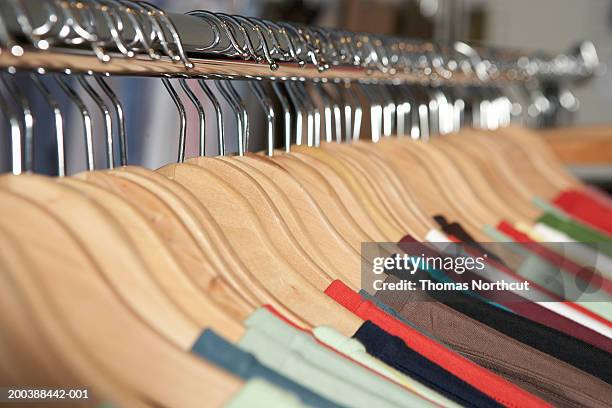 shirts on wooden hangers on clothes rack (focus on hangers) - rack focus stock-fotos und bilder