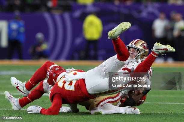 Christian McCaffrey of the San Francisco 49ers is hit by Justin Reid and Chamarri Conner of the Kansas City Chiefs during the second quarter during...