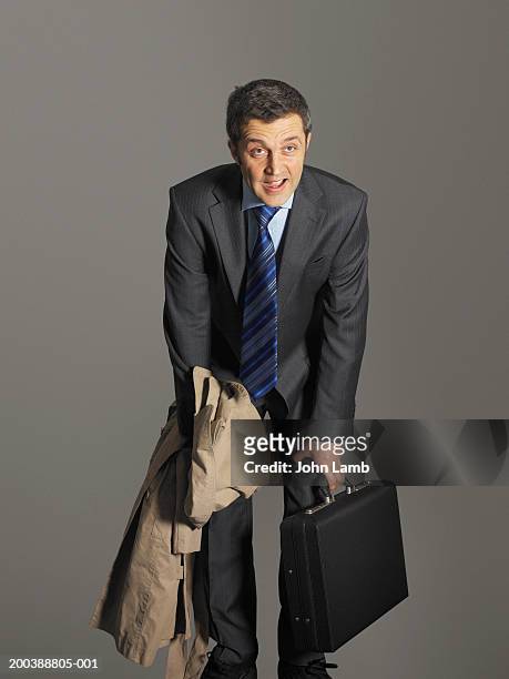 businessman with briefcase and coat, catching breath, hands on knees - 息切れ ストックフォトと画像