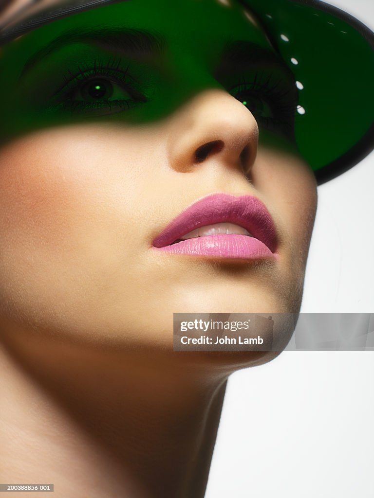 Young woman wearing sun visor, looking up, close-up