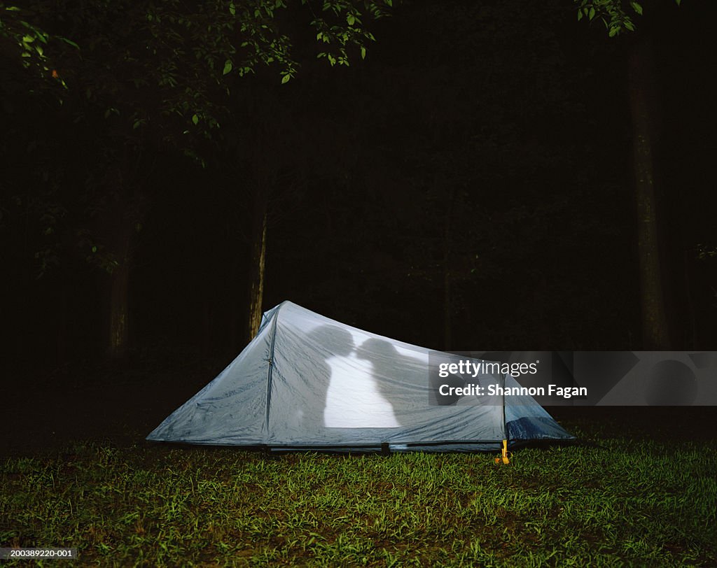 Silhouette of couple kissing in tent, night