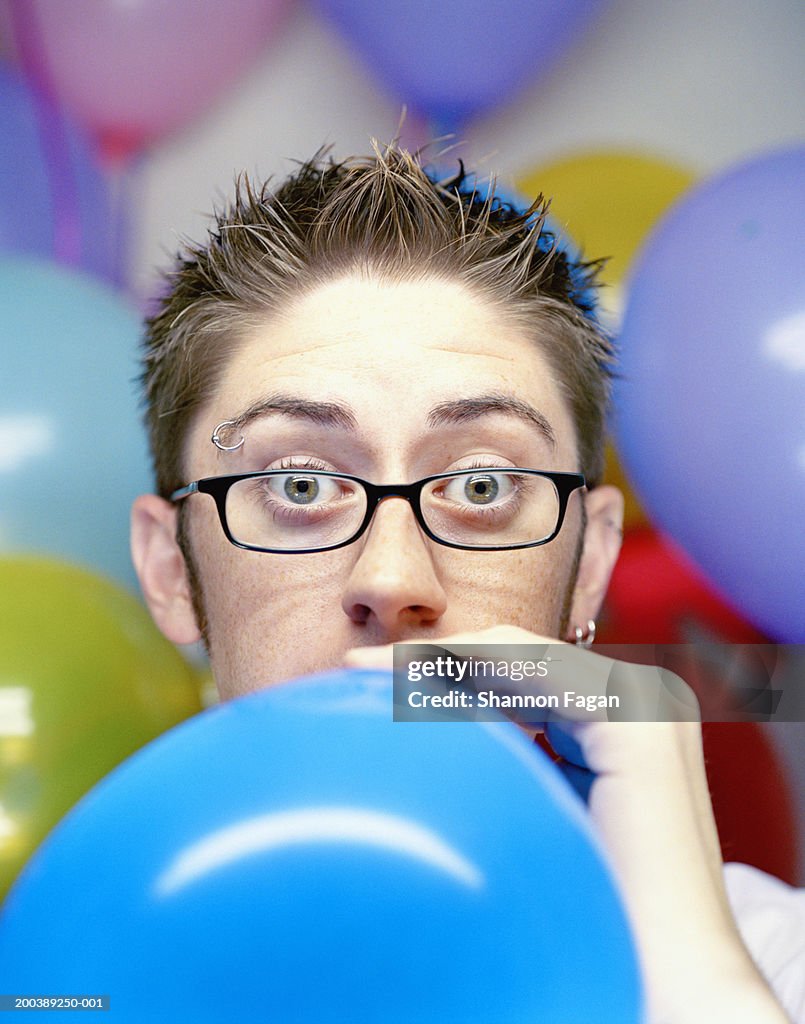 Young man inflating balloon at party, close-up