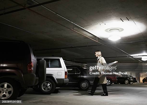 young businessman carrying blow-up doll in parking garage, side view - mann gummipuppe stock-fotos und bilder