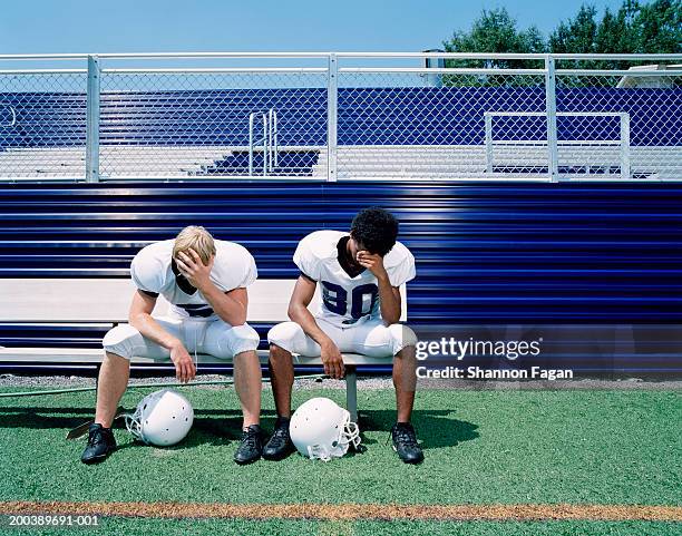 football players sitting on bench, hands to foreheads - banco de jogadores fotografías e imágenes de stock
