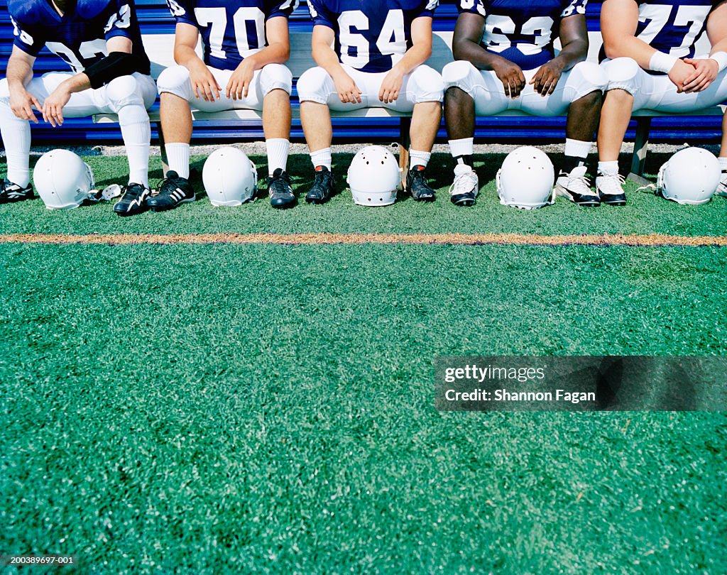 Football players sitting on bench, mid section