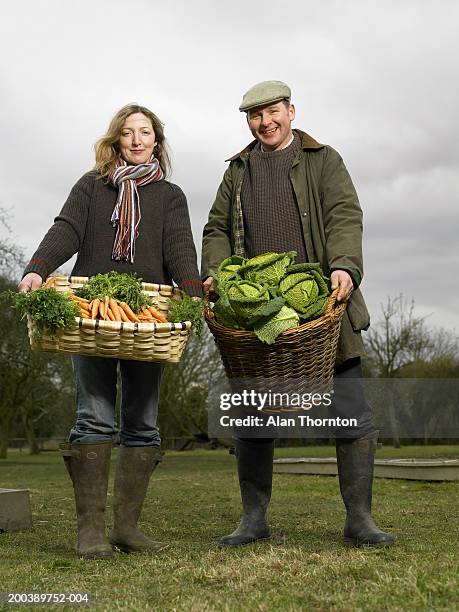 couple holding baskets of carrots and cabbages, smiling, portrait - leaf vegetable stock-fotos und bilder