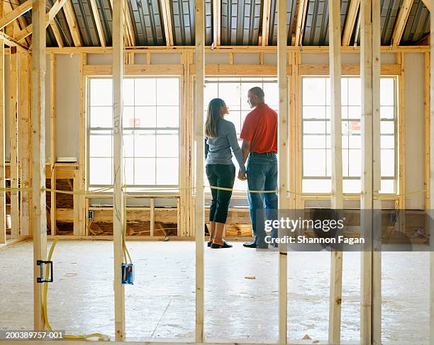 couple holding hands in home under construction, rear view - new hairstyle stock pictures, royalty-free photos & images