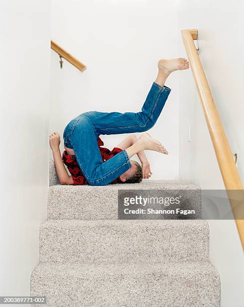 boy (11-13) tumbling on stairs, side view - piernas en el aire fotografías e imágenes de stock