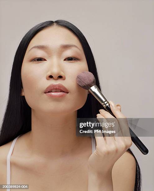 young woman applying make up brush, portrait - sminkborste bildbanksfoton och bilder