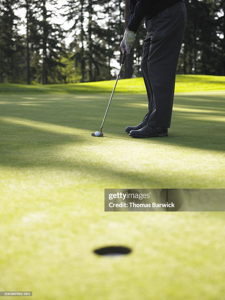 Senior man preparing to putt, low section, side view