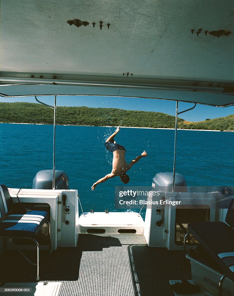 Man diving off back of boat, rear view